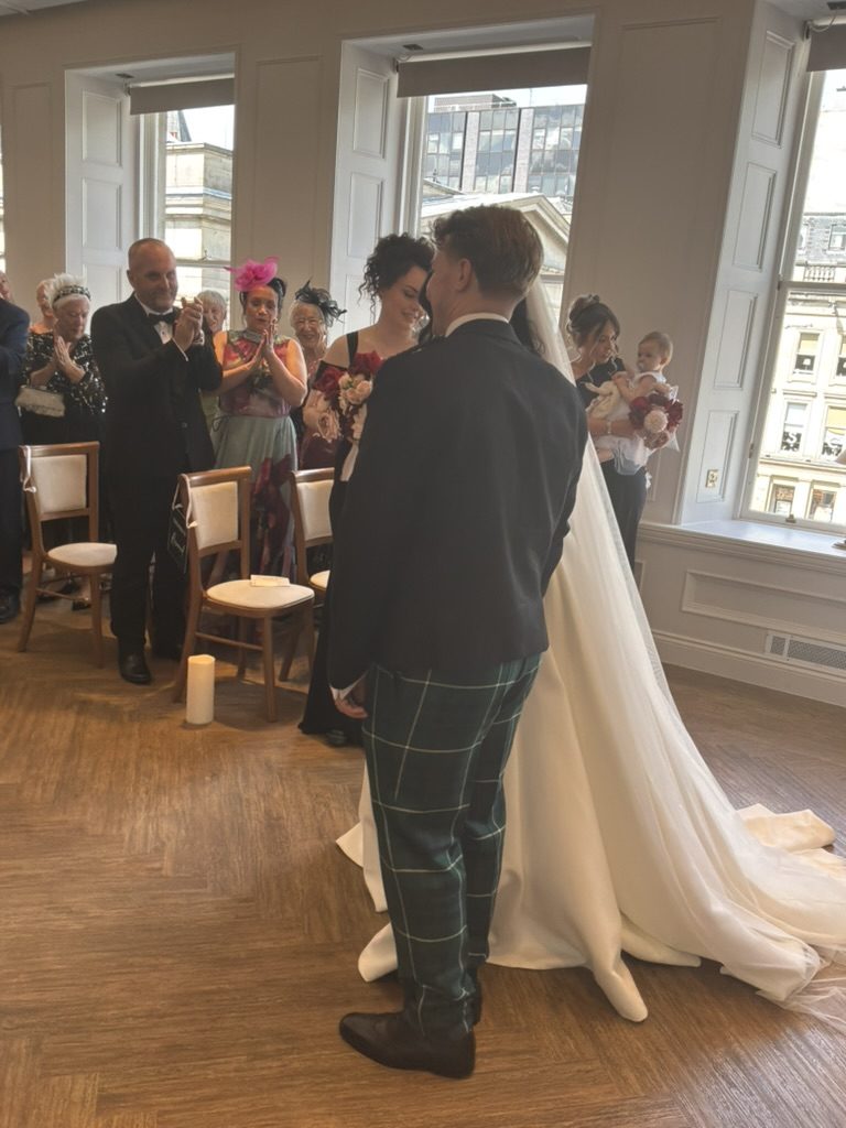 Aimee and Ollie during their ceremony at The Exchange, Royal Exchange Square through the windows