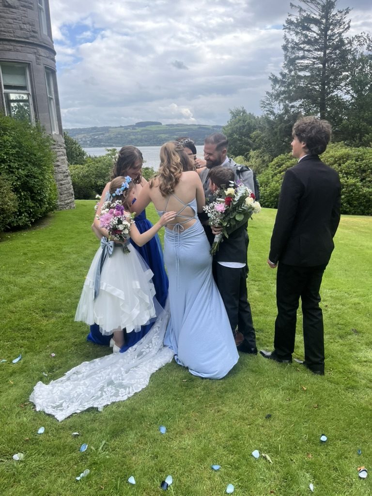 Sarah and Chris in a group hug with their children on the castle lawn at Cardross