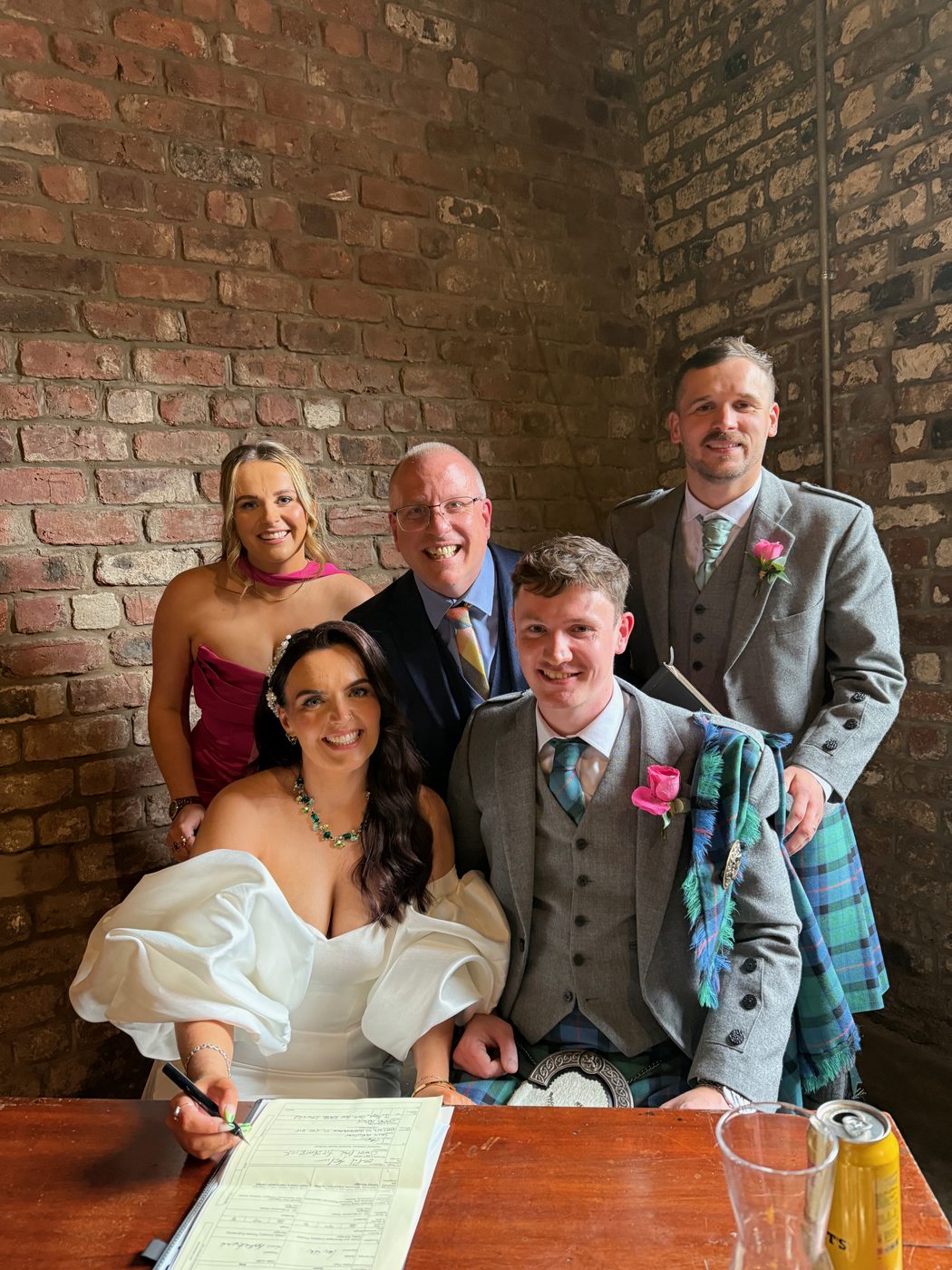 A couple in kilts signing the marriage schedule with John Paul and their witnesses