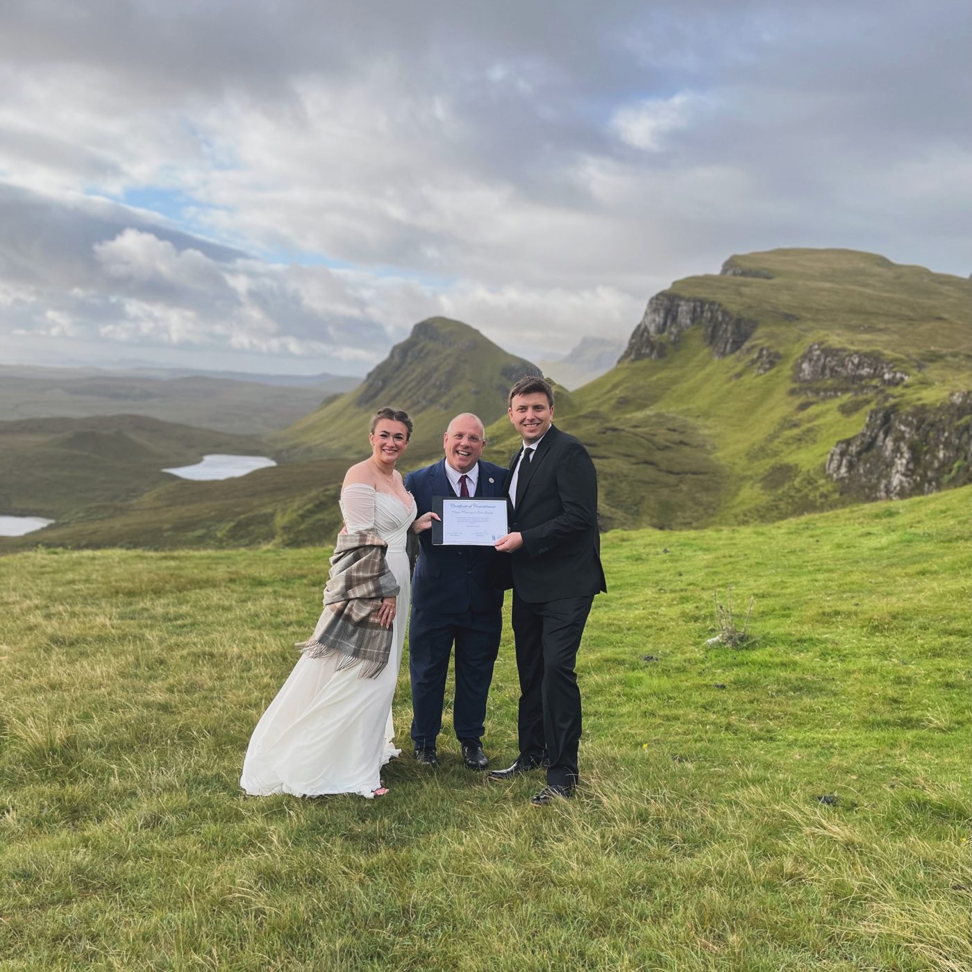 A wedding on the Quiraing, Isle of Skye — the couple and celebrant on the clifftop with Trotternish ridges behind